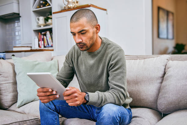 istock Shot of a young man using his digital tablet at home 1358212891