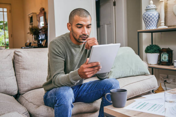 istock Shot of a young man using his digital tablet while relaxing at home 1358212892