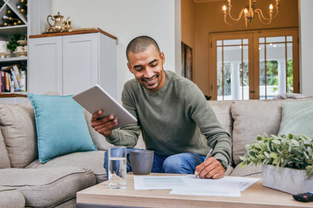 istock Shot of a man filling out paperwork while using his digital tablet 1358213289