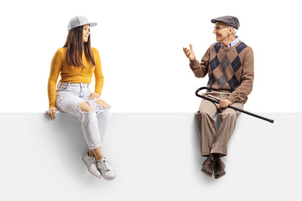 istock Young female and an elderly man sitting on a blank panel and having a conversation 1358214759