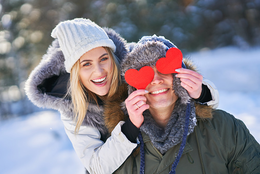 Couple with red hearts in winter snowy scenery. High quality photo