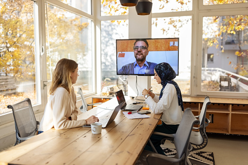 Business colleagues having a video conference. Startup business professionals making strategies sitting in board room with a colleague connecting on video call.