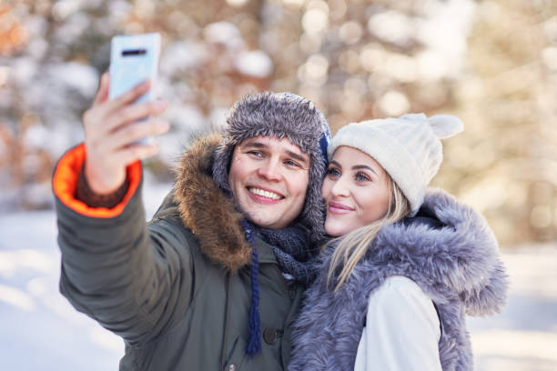 istock Young couple having fun on snow taking selfie 1358218388