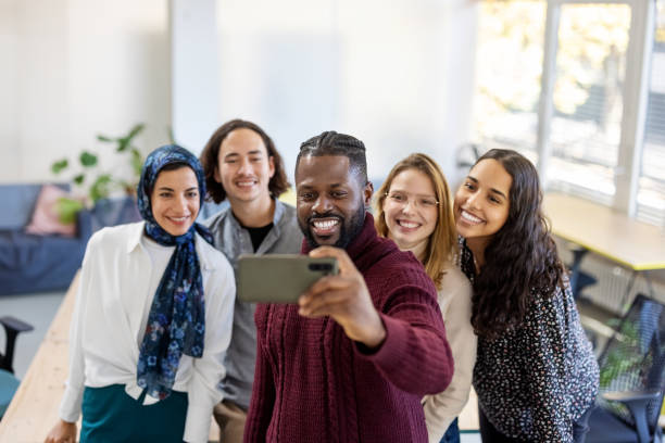 istock Cheerful startup team taking selfie at office 1358218489