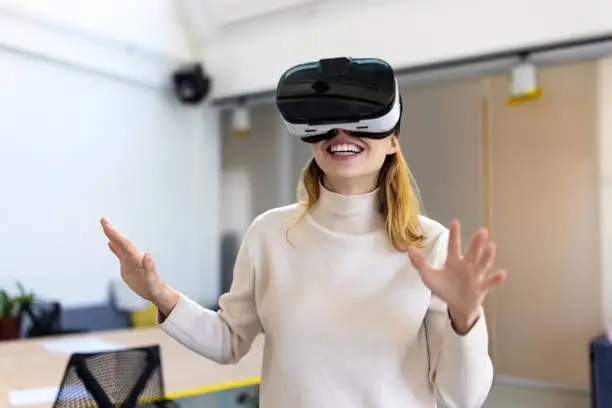 Young businesswoman wearing vr headset in office. Female executive testing the new virtual reality glasses.