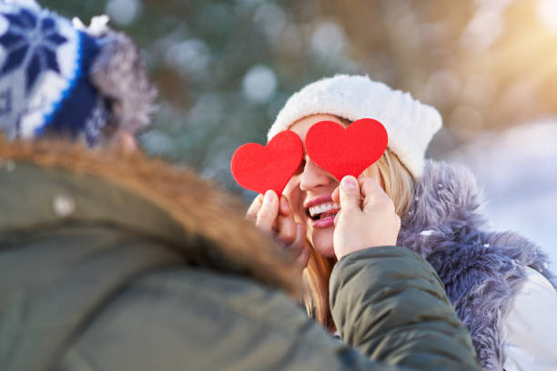 istock Couple with red hearts in winter snowy scenery 1358218734