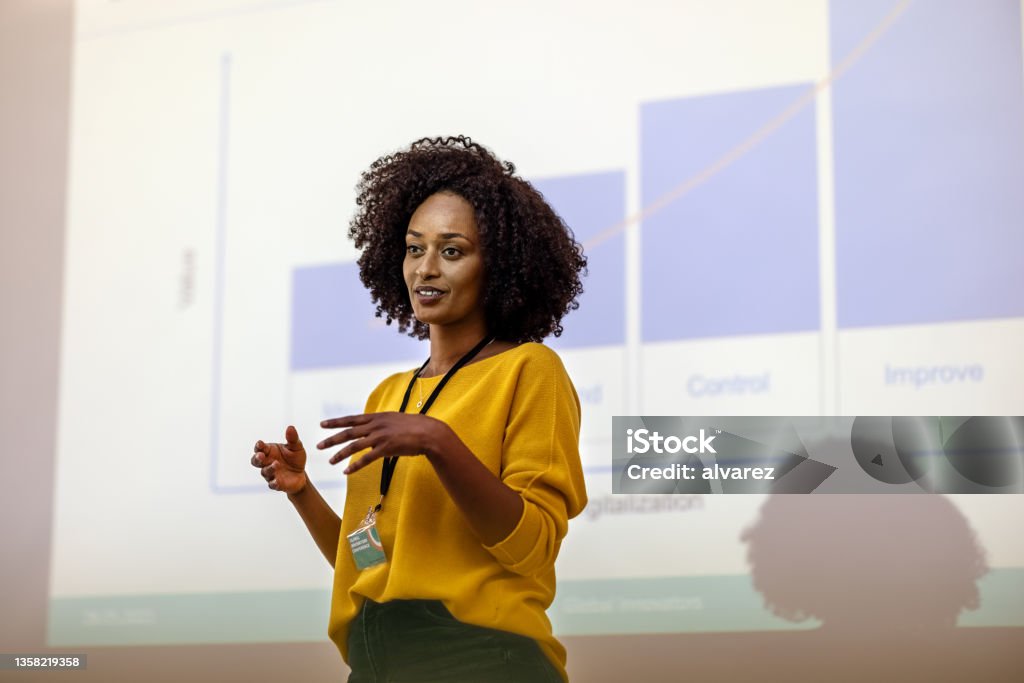 Woman entrepreneur at seminar giving presentation Woman entrepreneur speaking in the auditorium at the corporate training event. Woman at seminar giving a presentation. Presentation - Speech Stock Photo