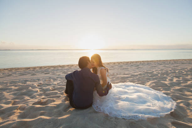 istock bride and groom sit on the sand 1358219857
