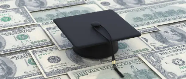 Photo of College cost, student loan, scholarship. Graduate cap on dollar banknotes. 3d illustration