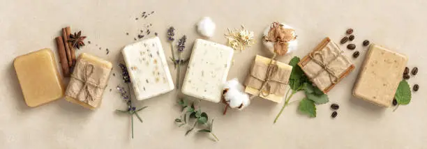 Photo of Natural soap bars and ingredients on beige background, flat lay