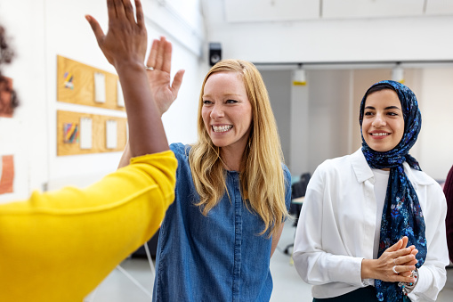 Female entrepreneurs give each other high-fives at office. Businesswomen celebrating a win with high-fives at the startup office.