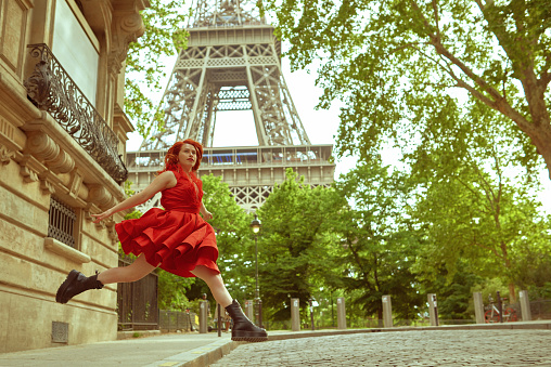 Dynamic caption with redhead woman while jumping on the streets facing the camera