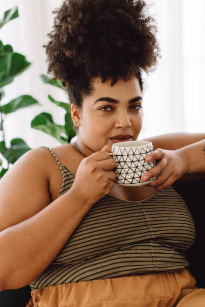 istock Woman drinking coffee and looking at camera 1358225108