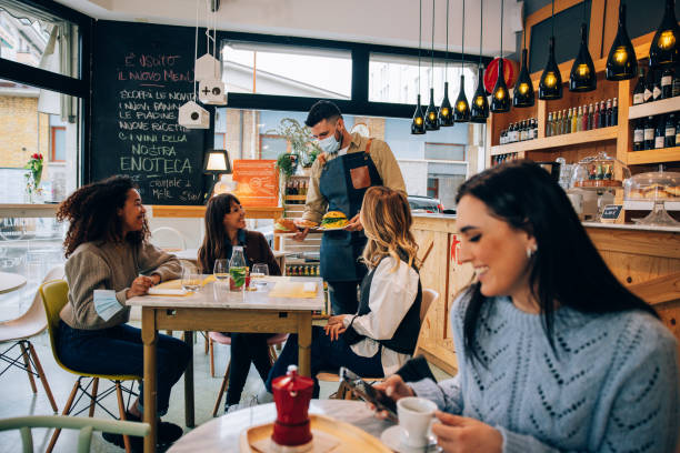 istock Waiter serving a table with a group of friends out for lunch 1358228249