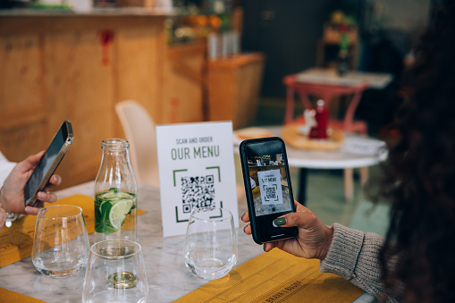 Woman consulting the restaurant menu with QR Code