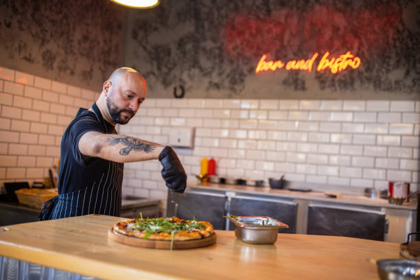 istock Skilled young Caucasian pizza master adding parmesan cheese on pizza 1358229057