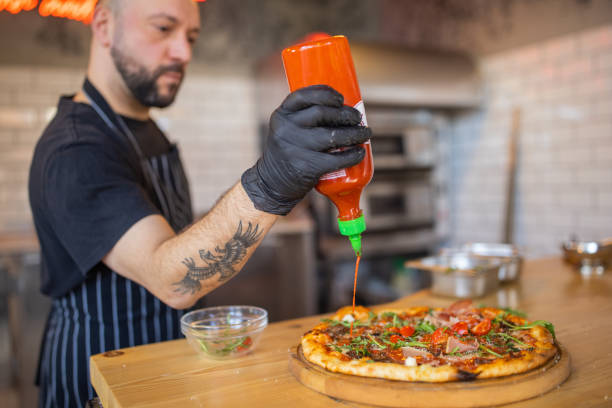 Pizza master adding the hot sauce on the pizza