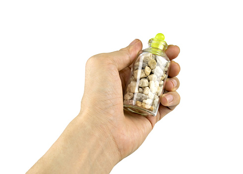 Hand holding Stones or gravel  in a glass bottle isolated on white background with clipping path.Concept Benefits of Stone.