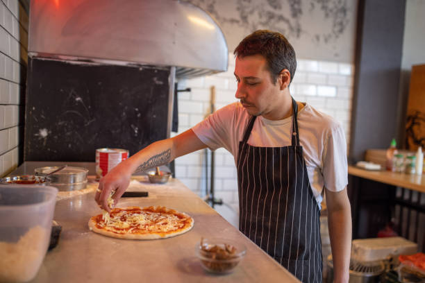 istock Skilled pizza master adding cheese on the top of the pizza 1358230826