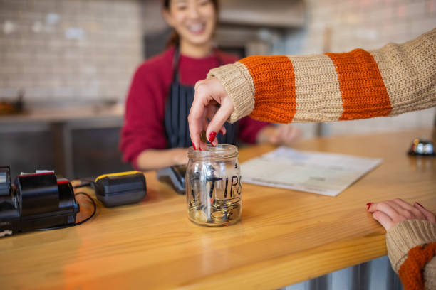 Unrecognizable female customer leaving the tips at the tip jar Unrecognizable female customer leaving the tips at the tip jar leaving a tip stock pictures, royalty-free photos & images