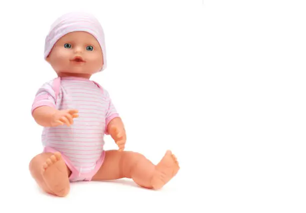 Toy baby doll in pink clothes and hat on white.