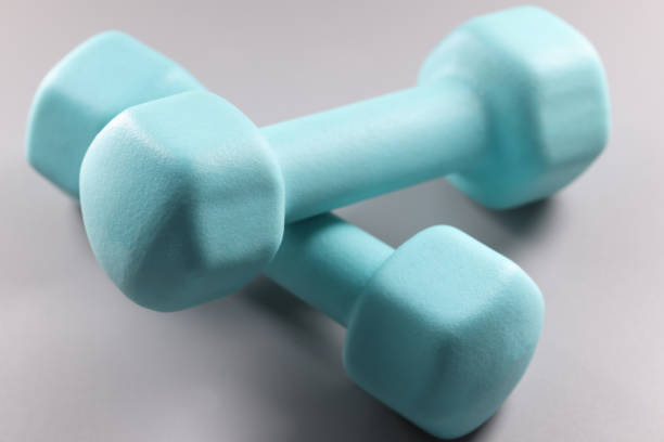 istock Blue two kilogram dumbbells on gray background 1358235812