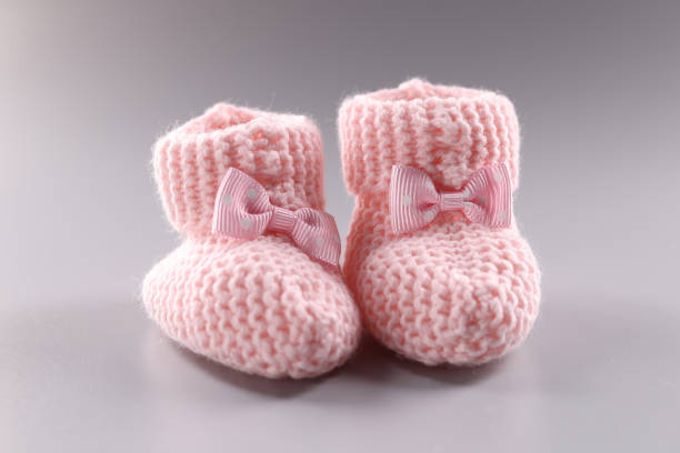 Pink knitted slippers for newborn on gray background Pink knitted slippers for newborn on gray background. Baby feet in shape of woman feet baby booties stock pictures, royalty-free photos & images