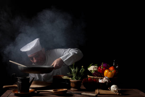 Male cook in white uniform and hat while working in a restaurant kitchen