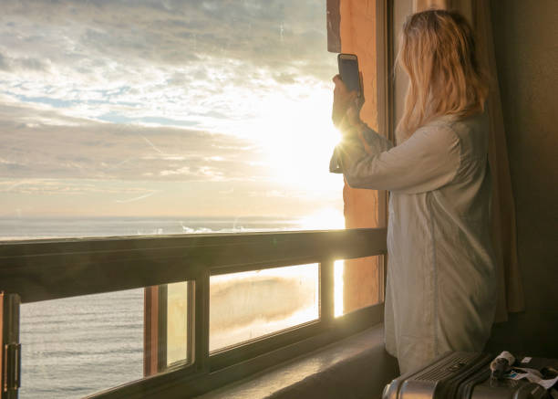 istock Woman relaxes by window, overlooking beach 1358249193