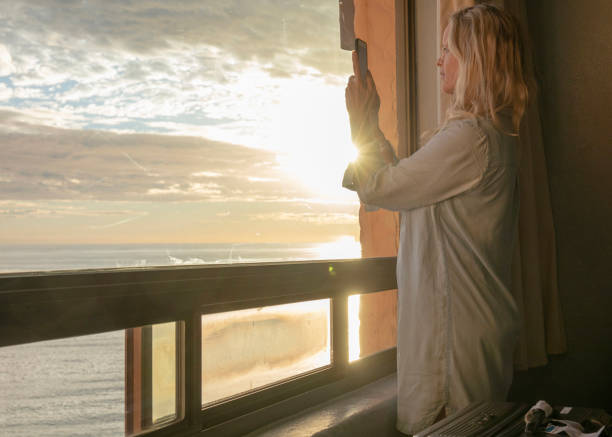 istock Woman relaxes by window, overlooking beach 1358249359
