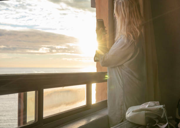istock Woman relaxes by window, overlooking beach 1358249434
