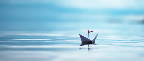 Paper Boat sailing on blue Water