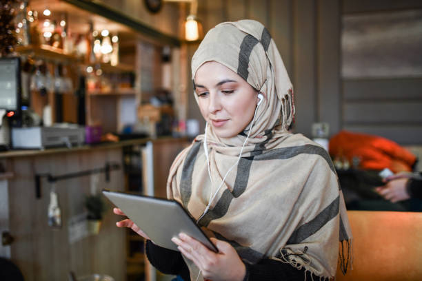 mulher muçulmana curtindo música em tablet digital em casa - arab style audio - fotografias e filmes do acervo