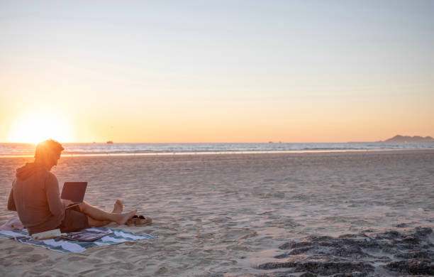 istock Man relaxes on sandy beach at sunrise 1358250723