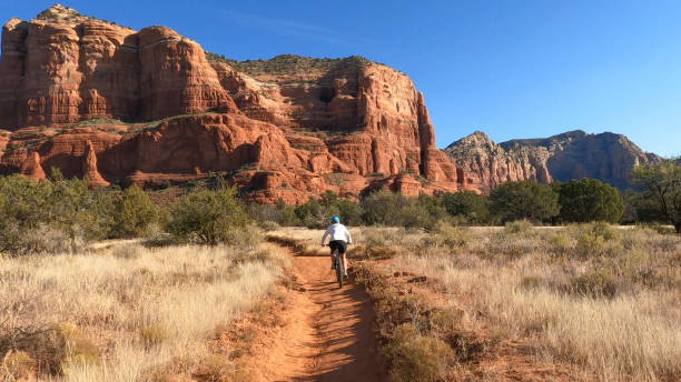 mujer ciclista de montaña sigue el sendero, en el desierto - sedona fotografías e imágenes de stock