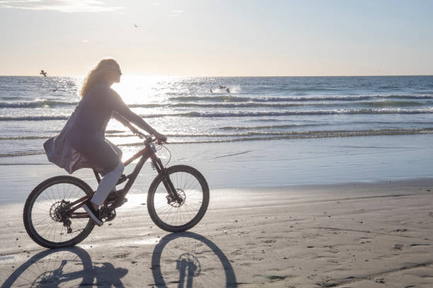 istock Woman bikes down empty beach, at sunrise 1358251209