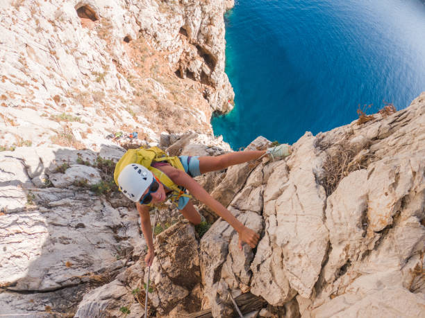 Climber on Via Ferrata above sea, young women climbing up the rock above sea stock photo