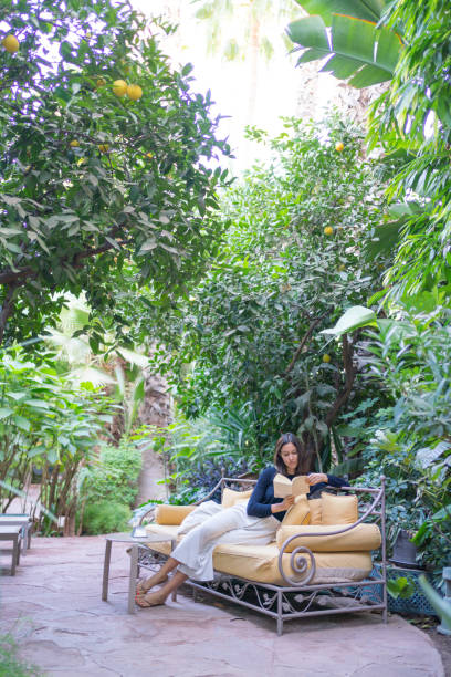 młoda kobieta relaksuje się na kanapie z książką w ogrodzie - 4719 zdjęcia i obrazy z banku zdjęć