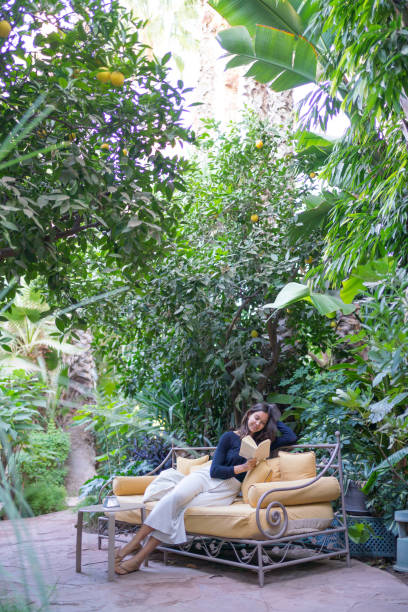 mujer joven se relaja en el sofá con libro en el jardín - outdoors book reading accessibility fotografías e imágenes de stock