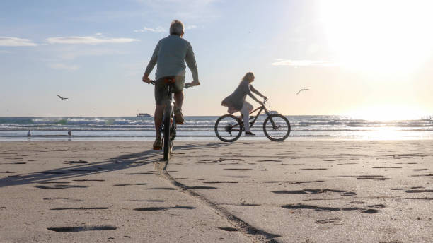 istock Couple mountain bike down empty beach 1358253466