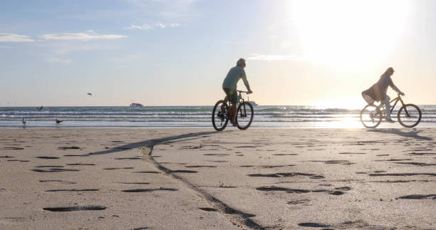 couple vtt sur la plage vide - senior couple cycling beach bicycle photos et images de collection
