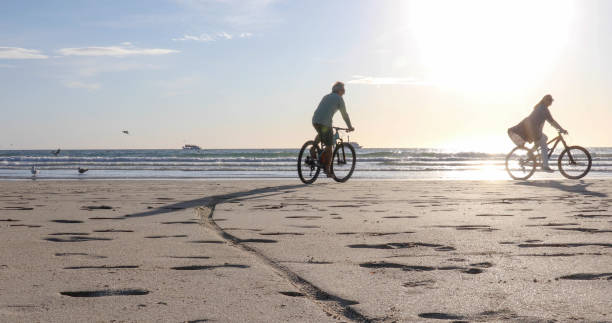 istock Couple mountain bike down empty beach 1358253585