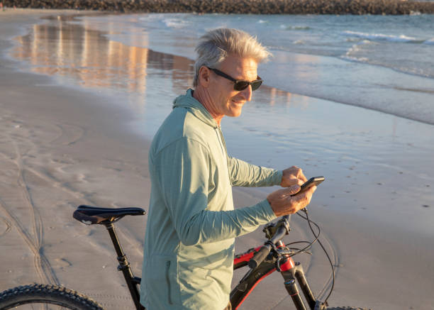 istock Man walks bike down empty beach, at sunrise 1358255373