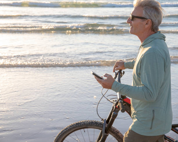 istock Man walks bike down empty beach, at sunrise 1358255391