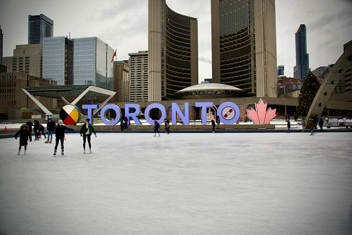 Toronto, Ontario, Canada= December 9th, 2021: People ice skating at Toronto city hall’s Nathan Phillips Square.