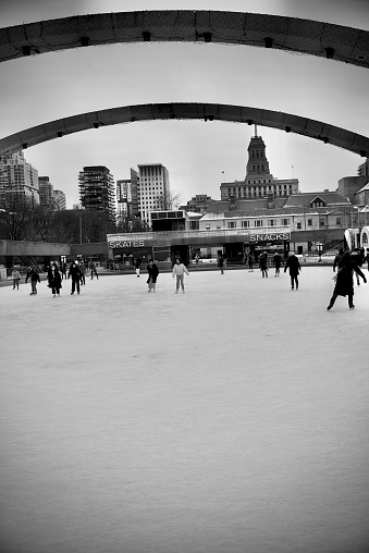 Toronto, Ontario, Canada- December 9, 2021: A view of Toronto city hall’s Nathan Phillips Square looking towards Queen street with people skating.