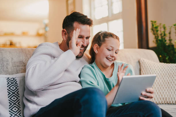 istock Shot of a father and daughter using a digital tablet on a live call together on the sofa at home 1358256607