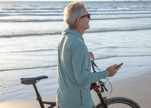 istock Man walks bike down empty beach, at sunrise 1358256875