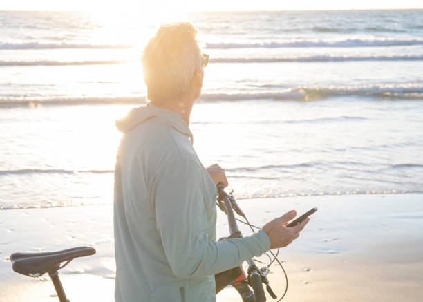 istock Man walks bike down empty beach, at sunrise 1358257138