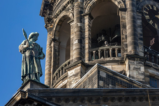 Amsterdam, Netherlands - January 9, 2021: close-up of the facade of the Royal Palace in Amsterdam with sculptures and dome with golden clock